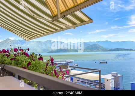 Terrasse des Cafés auf Scadar See in der Nähe Dock mit touristischen Booten Stockfoto