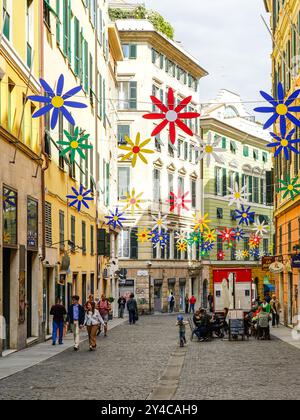 Genua, Italien – 27. Mai 2024: Via Garibaldi in Genua mit Girlanden aus bunten Blumen geschmückt, Beispiel für Street Art Stockfoto