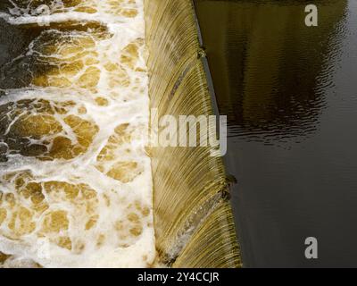 Wasser im Fluss, das durch ein Wehr fließt. Stockfoto