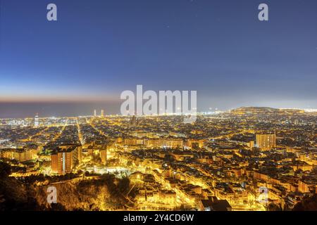 Die Skyline von Barcelona mit dem Mittelmeer im Hintergrund bei Nacht Stockfoto