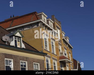 Altes Gebäude mit dekorativen Ziegeln, weißen Fensterrahmen und rotem Dach vor blauem Himmel, winterswijk, niederlande Stockfoto