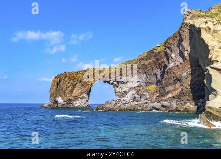 Das Wahrzeichen des Salinas Felsenbogens Punta Perciato entstand aus vulkanischer Lava im kristallklaren Meer in Sizilien in Italien Stockfoto