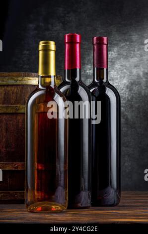 Drei Flaschen Wein in der Nähe von holzfass im Keller Stockfoto