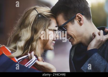 Foto, das junge Paare beim Einkaufen in der Stadt zeigt. Porträt eines Paares mit Einkaufstaschen in der Stadt. Menschen, Verkauf, Liebe und Glück Konzept Stockfoto