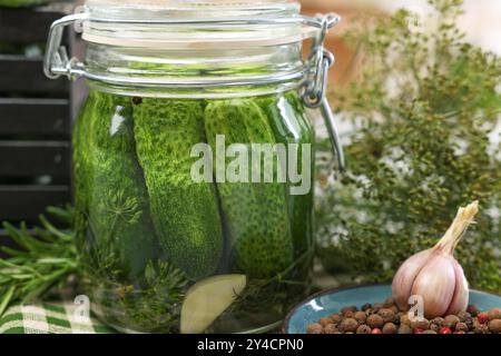 Eingelegte Gurken im Glas, Kräuter und Gewürze auf dem Tisch, Nahaufnahme Stockfoto