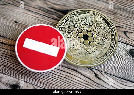 KIEW, UKRAINE - 17. AUGUST 2024 Cardano ADA Münze und rotes Papier Stoppschild auf hölzernem Hintergrund Nahaufnahme Stockfoto