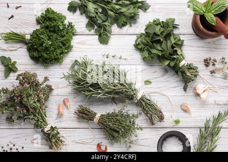 Verschiedene aromatische Kräuter auf weißem Holztisch, flach gelegen Stockfoto