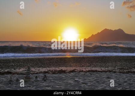 Landkunst vor den Surfwellen bei Sonnenuntergang am Strand von Porto, Korsika Stockfoto