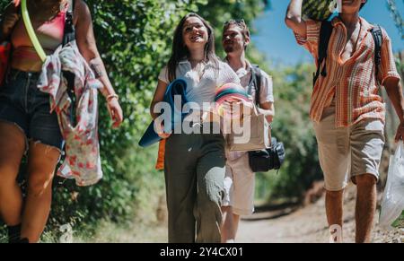 Gruppe von Freunden, die an einem sonnigen Tag mit Picknickvorräten im Freien spazieren gehen Stockfoto