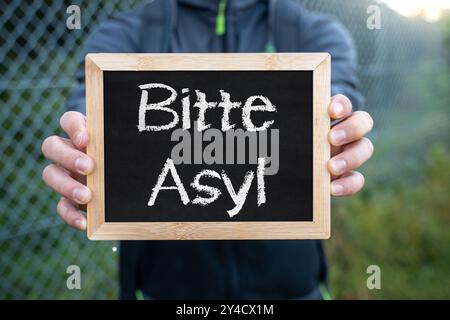 17. September 2024: Eine Person hält ein Schild mit der Aufschrift: Bitte Asyl. Symbolisches Image für Asylbewerber und Flüchtlingsanträge. FOTOMONTAGE *** eine Person hält ein Schild mit der Aufschrift: Bitte Asyl. Symbolbild für Asylsuche und Flüchtlingsanträge. FOTOMONTAGE Stockfoto