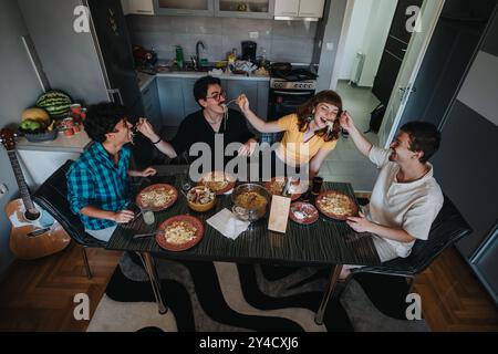 Freunde genießen ein Pasta-Essen zusammen in einer gemütlichen Küche Stockfoto