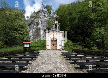 Kleine, sonnendurchflutete Kapelle, die am Fuß eines Felsens errichtet wurde Stockfoto