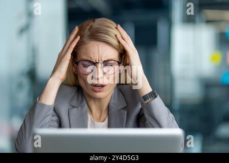 Geschäftsfrau mit Brille fühlt sich während der Arbeit im Büro gestresst und frustriert. Frau drückt im beruflichen Umfeld Angst und Druck aus. Konzept des Stressmanagements Stockfoto