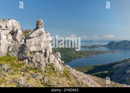 Felsiger Bergkamm mit Steinpyramide und Meer mit Inseln im Hintergrund, Lofoten Norwegen Stockfoto