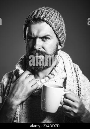 Stilvoller bärtiger Mann, der Kaffee, Cappuccino oder Tee aus der Tasse trinkt. Modischer Mann, der Kaffee im Café trinkt. Gutaussehender Mann mit Bart und Schnurrbart im Hut Stockfoto