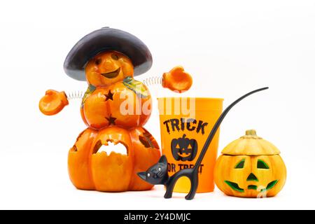 Halloween-Display mit einem Jack o Laterne, Kürbiskerzenhalter, kürbisförmigem Plastikbecher und einer schwarzen Katzenfigur auf weißem Hintergrund Stockfoto