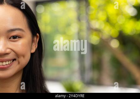 Lächelnde junge asiatische Frau mit langen Haaren, die einen hellen und fröhlichen Tag genießt, Kopierraum Stockfoto