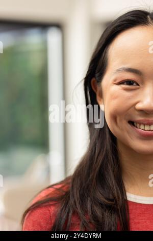 Lächelnde junge asiatische Frau mit langen Haaren, rotes Hemd, Blick in die Kamera, Kopierraum Stockfoto