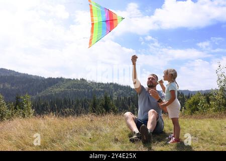 Vater mit Tochter, die Drachen auf dem Feld fliegt Stockfoto