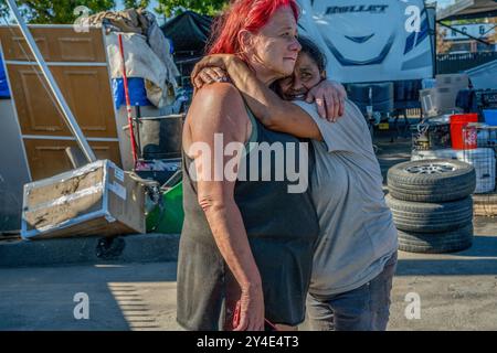 Sacramento, Kalifornien, USA. August 2024. Camp Resolution Residents TWANA JAMES, 55, links, und JULIE MAESTAS, 48, richtig, umarmen, als Sacramento Fire Marshall Jason Lee das eng gestrickte selbstverwaltete Obdachlosenlager in Sacramento wiederbesucht. Sie waren die ganze Nacht wach, um das Lager vorzubereiten, damit es nach Lees Besuch vor zwei Wochen eine Sicherheitsinspektion bestehen würde. Das Lager der meist älteren Frauen mit Behinderungen und Haustiere hofften, wenn sie die Inspektion bestanden hätten, könnte das zweijährige Lager erhalten bleiben. (Kreditbild: © Renee C. Byer/ZUMA Press Wire) NUR REDAKTIONELLE VERWENDUNG! Nicht für kommerzielle U Stockfoto