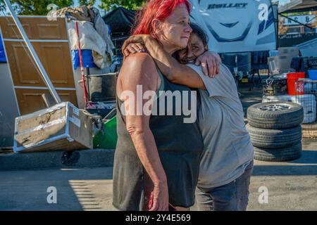 Sacramento, Kalifornien, USA. August 2024. Camp Resolution Residents TWANA JAMES, 55, links, und JULIE MAESTAS, 48, richtig, umarmen, als Sacramento Fire Marshall Jason Lee das eng gestrickte selbstverwaltete Obdachlosenlager in Sacramento wiederbesucht. Sie waren die ganze Nacht wach, um das Lager vorzubereiten, damit es nach Lees Besuch vor zwei Wochen eine Sicherheitsinspektion bestehen würde. Das Lager der meist älteren Frauen mit Behinderungen und Haustiere hofften, wenn sie die Inspektion bestanden hätten, könnte das zweijährige Lager erhalten bleiben. (Kreditbild: © Renee C. Byer/ZUMA Press Wire) NUR REDAKTIONELLE VERWENDUNG! Nicht für kommerzielle U Stockfoto