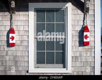 Rote und weiße Vintage-Hummerbojen mit dem roten kanadischen Ahornblatt, der kanadischen Flagge, hängen vor dem Büro des Hafenmeisters an der Market Wharf in der Passamaquoddy Bay im Zentrum von Saint Andrews, New Brunswick, Kanada. Stockfoto