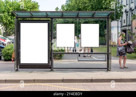 Drei leere vertikale Mockups von Reklametafeln an der Bushaltestelle vor Einem Stadtpark. Leere Weiße Werbeflächen Auf Dem Bürgersteig Stockfoto