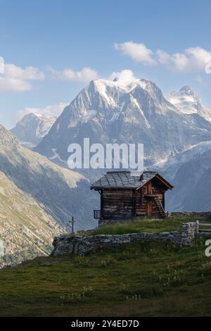 Blick auf die Sommerlandschaft eines typischen Schweizer Chalets vor dem schneebedeckten Gipfel des Mont Collon. Stockfoto