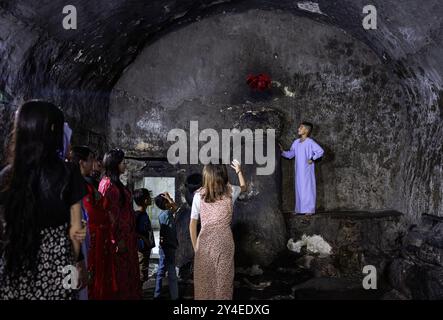 Lalisch, Irak. September 2024. Eine Jesidin wirft ein rotes Tuch auf einen Stein in Lalish, der heiligsten Stätte der Jesiden. Bleibt das Tuch auf dem Stein, erfüllt sich ihr Wunsch. Quelle: Hannes P. Albert/dpa/Alamy Live News Stockfoto