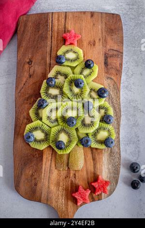 Obstweihnachtsbaum aus Kiwis, Heidelbeeren und Wassermelone auf einer Holzplatte Stockfoto