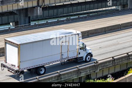 Industrieller örtlicher Transportunternehmer, mittlerer Dienst, Day Cab, weißer Lkw, der Ladung im Kühlkasten transportiert, Anhänger mit zur Lieferung laufender Seitentür Stockfoto