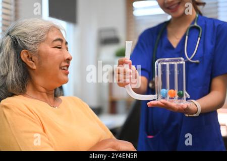 Physiotherapeut unterstützt reife Frauen bei der Verwendung eines Spirometers zur Verbesserung der Lungenfunktion Stockfoto