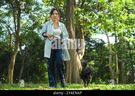 Die ganze Länge einer glücklichen jungen Frau, die mit ihrem Border Bollie Hund in der Natur geht Stockfoto