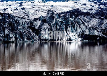 Solheimajokull-Gletscher bedeckt mit Ruß von früheren Eruptionen, wobei der Gletschersee vom Vulkan bei Vik in Island absteigt Stockfoto