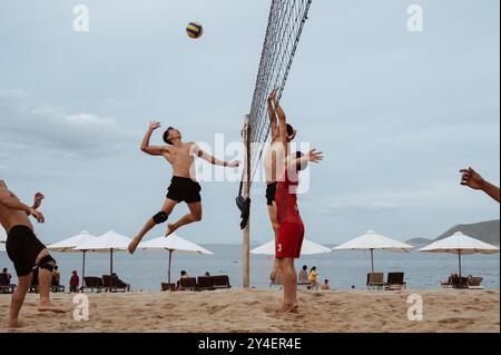 Asiatische vietnamesische Spieler spielen Beachvolleyball an einem Sandstrand am Meer während des Sommertages in Nha Trang. Nha Trang, Vietnam - 21. Juli 2024 Stockfoto