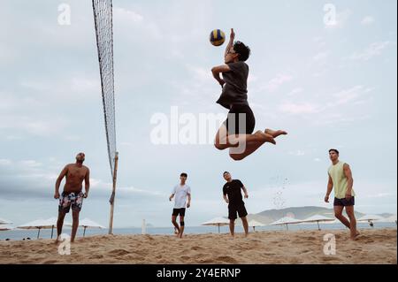 Asiatische vietnamesische Spieler spielen im Sommer Beachvolleyball an einem Sandstrand am Meer. Nha Trang, Vietnam - 21. Juli 2024 Stockfoto