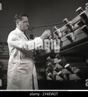 Howard Florey. 1898-1968. Australischer Pharmakologe, der 1945 den Nobelpreis für Physiologie oder Medizin mit Alexander Fleming und Ernst Chain erhielt. Obwohl Fleming den größten Teil der Anerkennung für die Entdeckung von Penicillin erhielt, waren es Florey und sein Team an der University of Oxford, die es zu einer nützlichen und wirksamen Droge machten, zehn Jahre nachdem Fleming seine Entwicklung aufgegeben hatte. Abgebildet im Labor des St. Marys Krankenhauses mit den Glasbehältern, die ursprünglich bei der Forschung von Penicillin verwendet wurden. KG Kristoffersson Ref. S87-1 (gescannt von seinem negativen Original im Großformat verfügbar auf Stockfoto