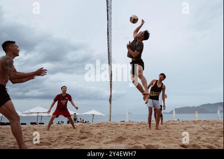Asiatische vietnamesische Spieler spielen im Sommer Beachvolleyball an einem Sandstrand am Meer. Nha Trang, Vietnam - 21. Juli 2024 Stockfoto