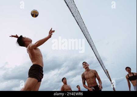 Asiatische vietnamesische Spieler spielen im Sommer Beachvolleyball an einem Sandstrand am Meer. Nha Trang, Vietnam - 21. Juli 2024 Stockfoto