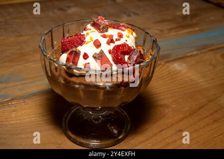 Eine köstliche Schokoladenmousse mit Creme Fraiche Cremes und Schokoladenstückchen auf einer hölzernen Küchenarbeitsfläche Stockfoto