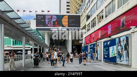 Hongkong, China - 18. September 2024 : Menschen laufen auf einem Bürgersteig in Hongkong, China. Sie laufen an einem großen Einkaufszentrum vorbei. Stockfoto