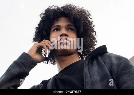 afrikanischer Teenager mit lockigen Haaren am Telefon Stockfoto