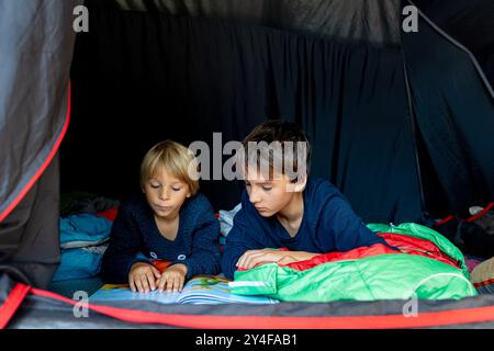 Kinder, Jungen Geschwister, genießen eine Nacht in einem Zelt im Camping, lachen und lesen Bücher Stockfoto