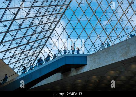 Paris (Frankreich): Touristen in der Halle des Louvre-Museums unter der Struktur der Großen Pyramide. Touristen auf der Treppe unter der Pyramide Stockfoto