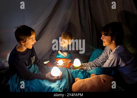 Kinder, Jungen Geschwister, genießen eine Nacht in einem Zelt im Camping, lachen und lesen Bücher Stockfoto