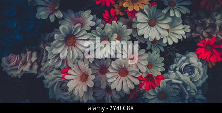 Ein Blumenstrauß aus künstlichen Blumen, darunter weiße Gänseblümchen, rosa Rosen und rote Blumen, mit einem Filter im Vintage-Stil. Stockfoto