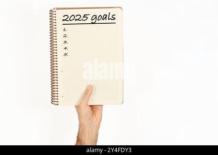 2025 Tore auf einem Notizbuch geschrieben, das ein Mann hält. Isoliert auf weißem Hintergrund. Stockfoto