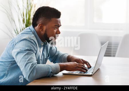 Junge afrikanische Arbeiter mit Laptop im Büro Stockfoto