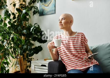 Eine junge Frau mit Alopezie sitzt bequem, genießt ihren Kaffee und denkt über ihren Tag nach. Stockfoto