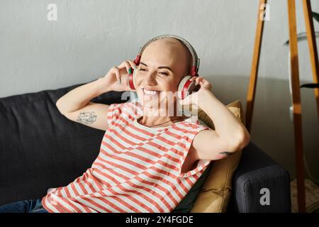 Die junge Frau, die ihre Kahlheit annimmt, strahlt Glück aus, während sie Musik hört. Stockfoto